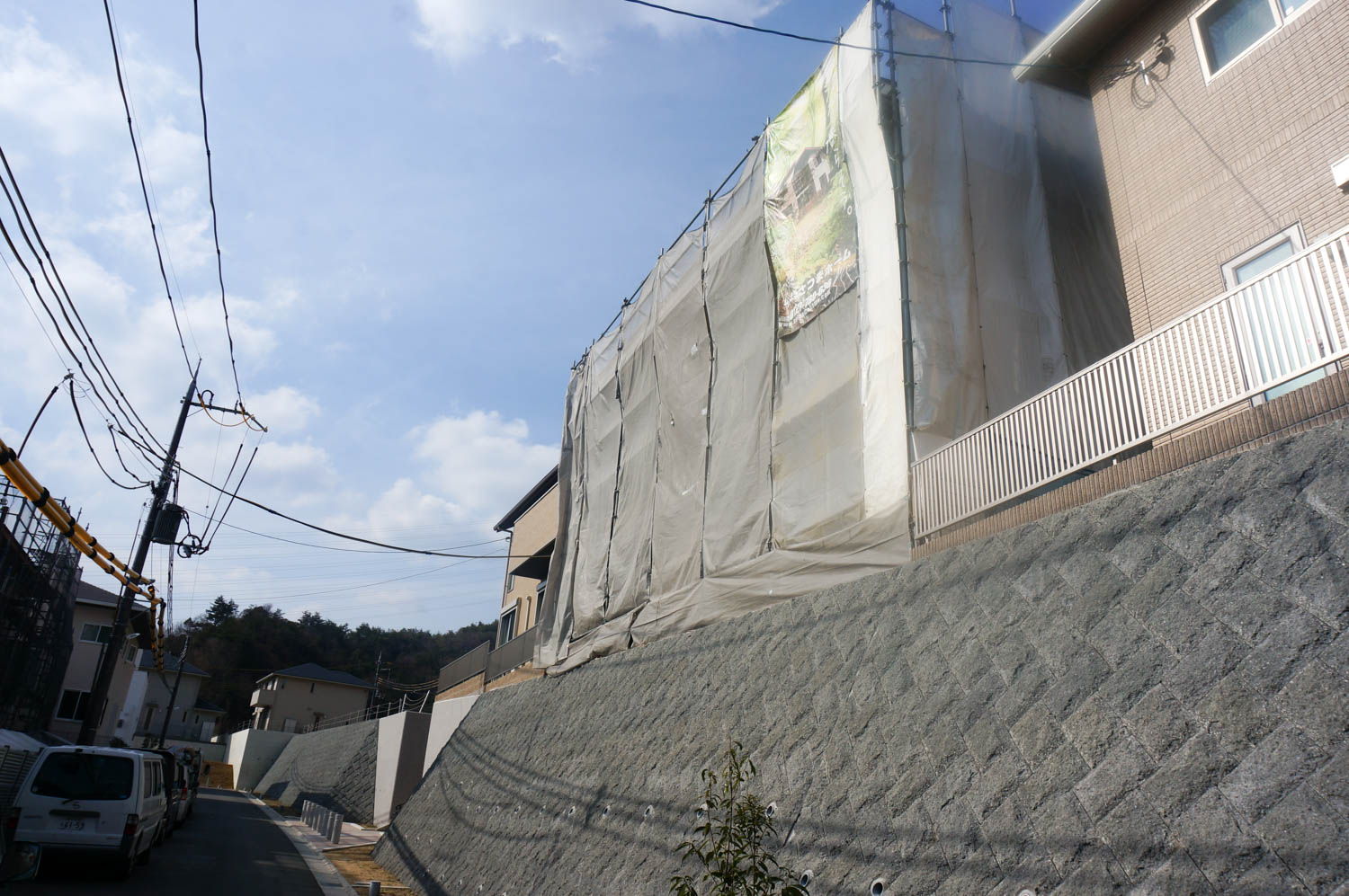 擁壁の上のウッドデッキとシンプルな外構