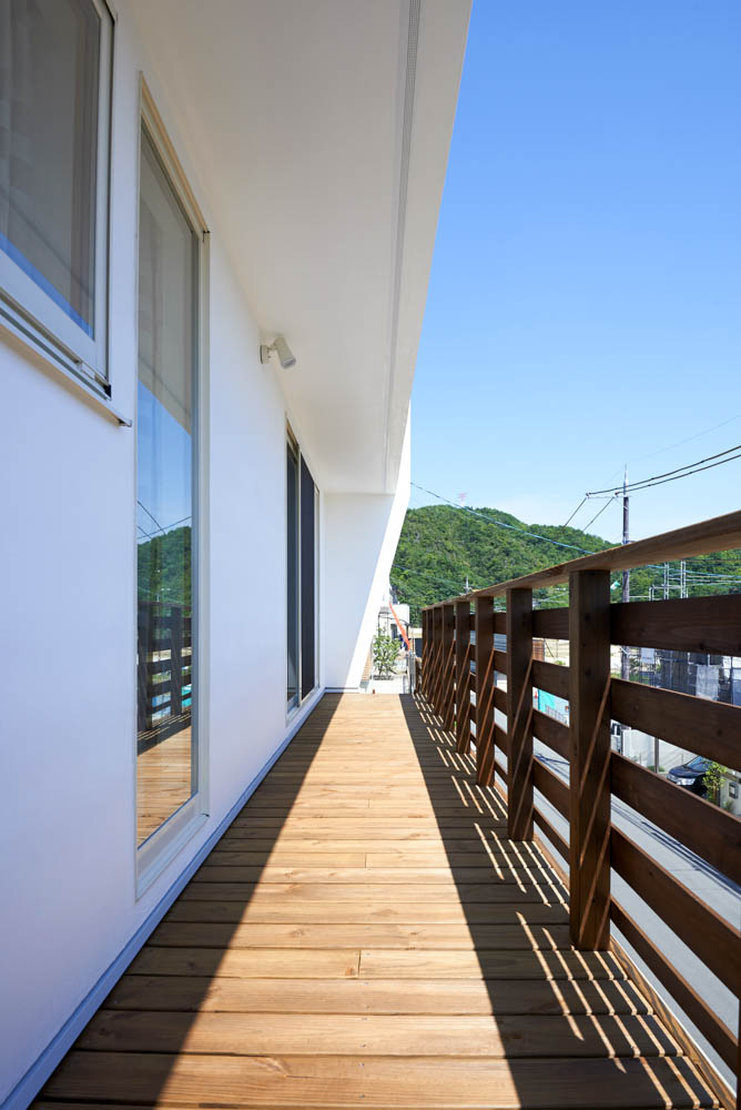 擁壁の上のウッドデッキとシンプルな外構