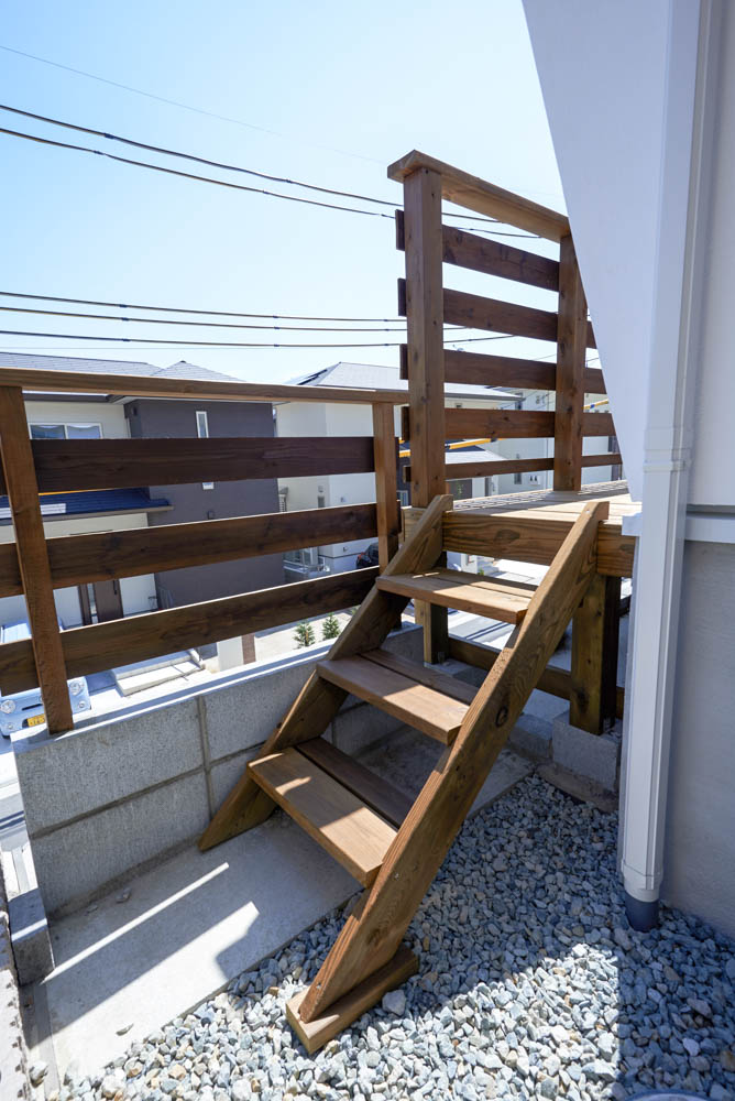 擁壁の上のウッドデッキとシンプルな外構