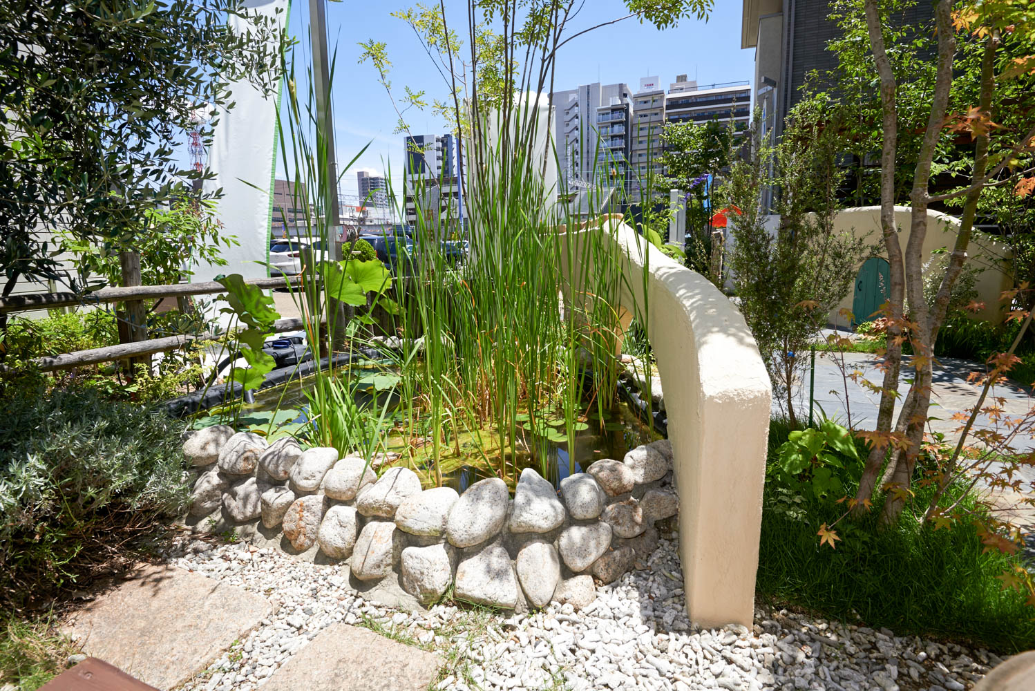 木製自転車小屋とビオトープとオリジナル立水栓のあるショップガーデン